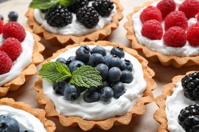 Photo of Many different berry tarts on table, closeup. Delicious pastries