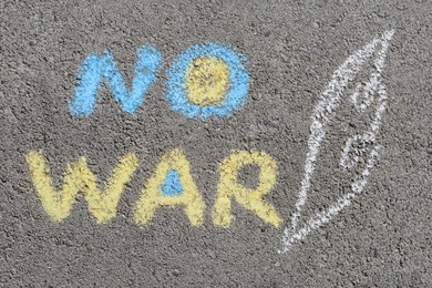 Photo of Words No War written with blue and yellow chalks on asphalt outdoors, top view