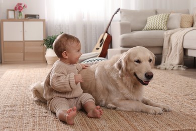 Photo of Cute little baby with adorable dog on floor at home