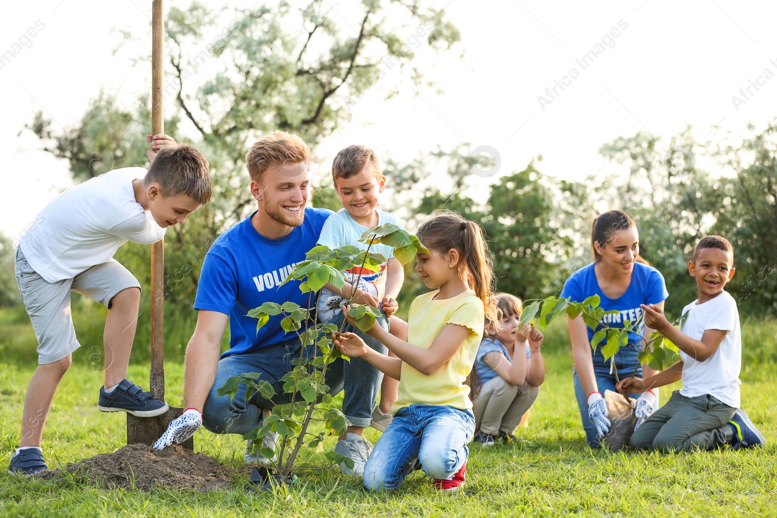 Photo of Kids planting trees with volunteers in park