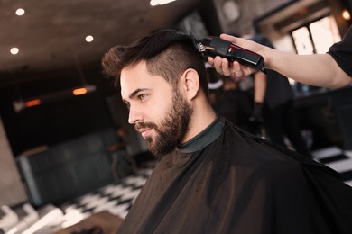 Professional hairdresser working with client in barbershop