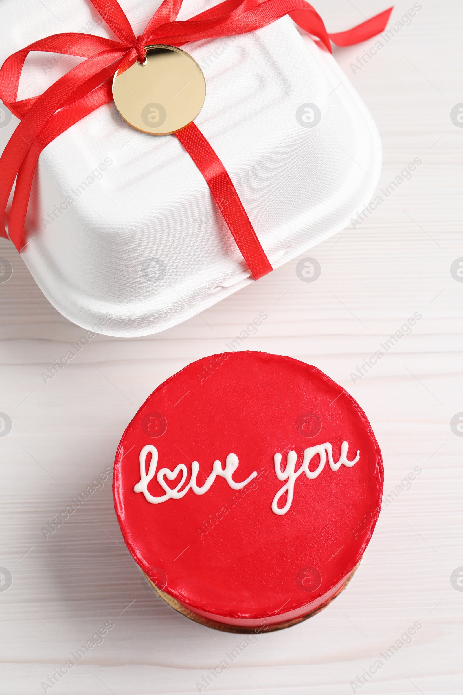 Photo of Bento cake with text Love You and takeaway packaging on white wooden table, flat lay. St. Valentine's day surprise