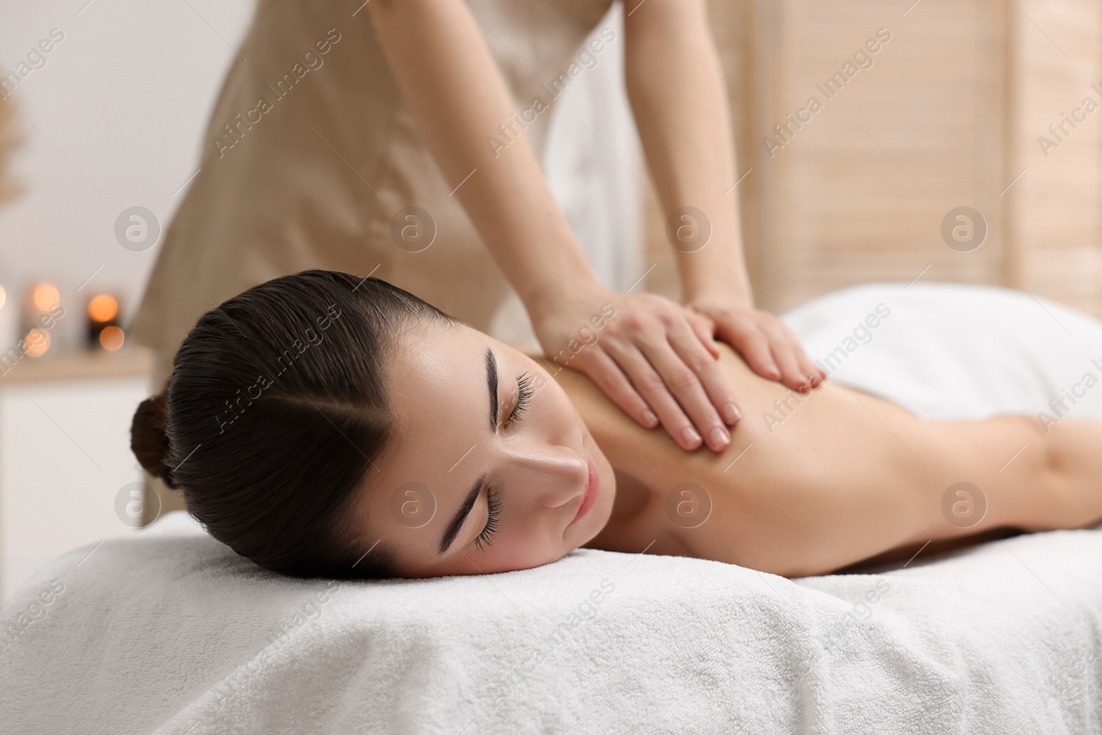 Photo of Woman receiving back massage on couch in spa salon