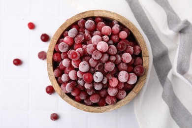 Photo of Frozen red cranberries in bowl on white tiled table, top view