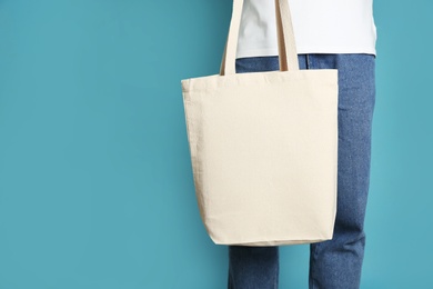 Photo of Man with cotton shopping eco bag on color background. Mockup for design