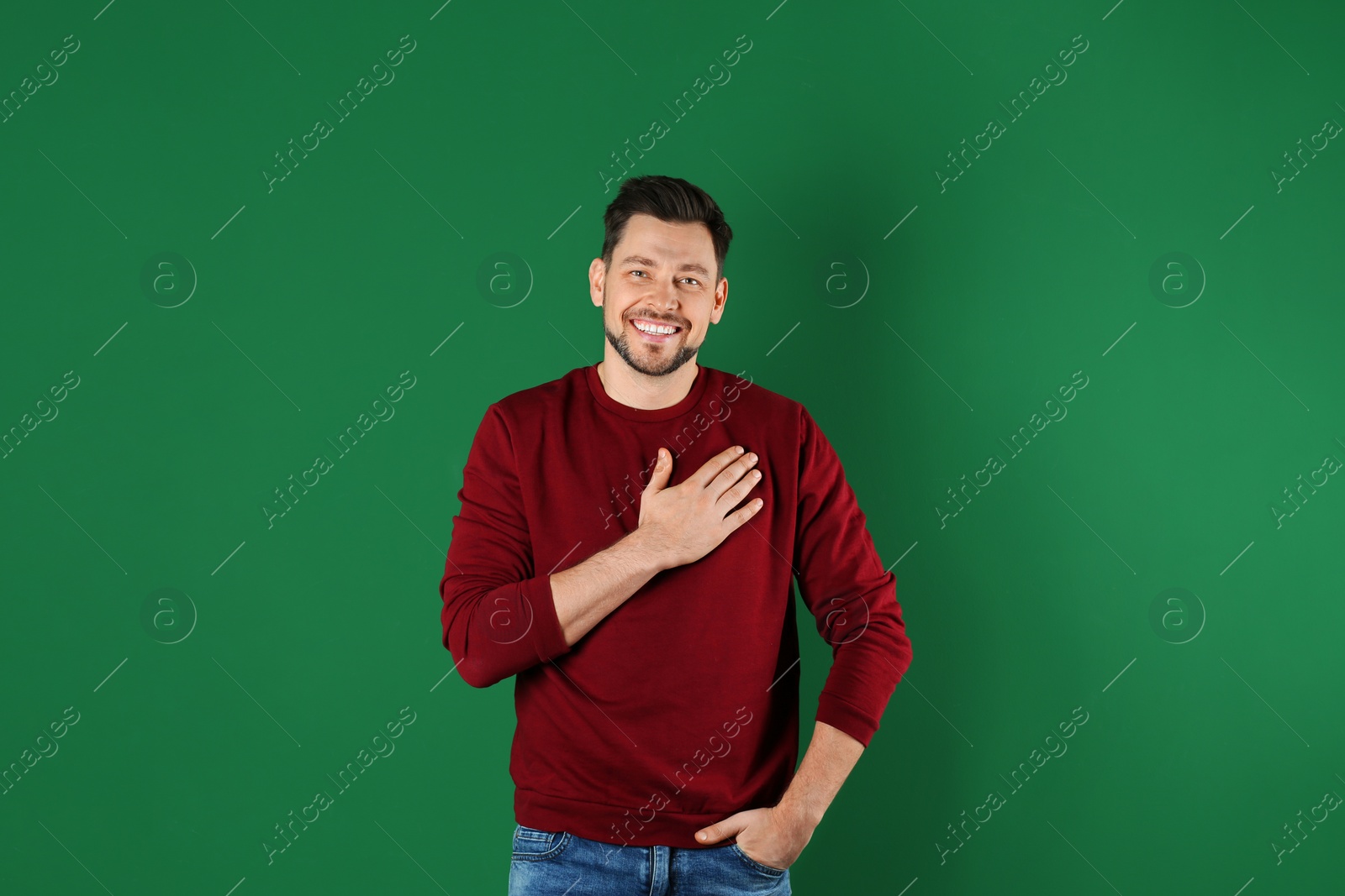 Photo of Portrait of handsome man holding hand near his heart on color background