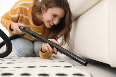 Young woman using vacuum cleaner at home