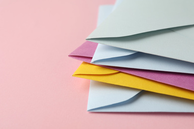 Stack of colorful paper envelopes on pink background, closeup. Space for text