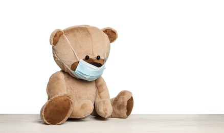 Photo of Cute teddy bear in medical mask isolated on white