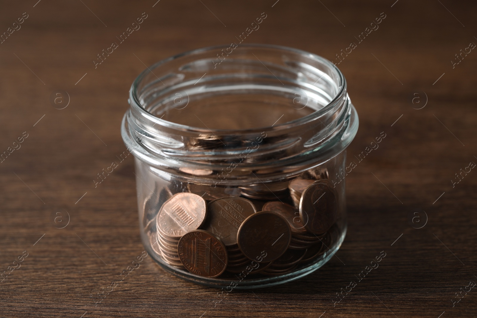 Photo of Glass jar with coins on wooden table, closeup