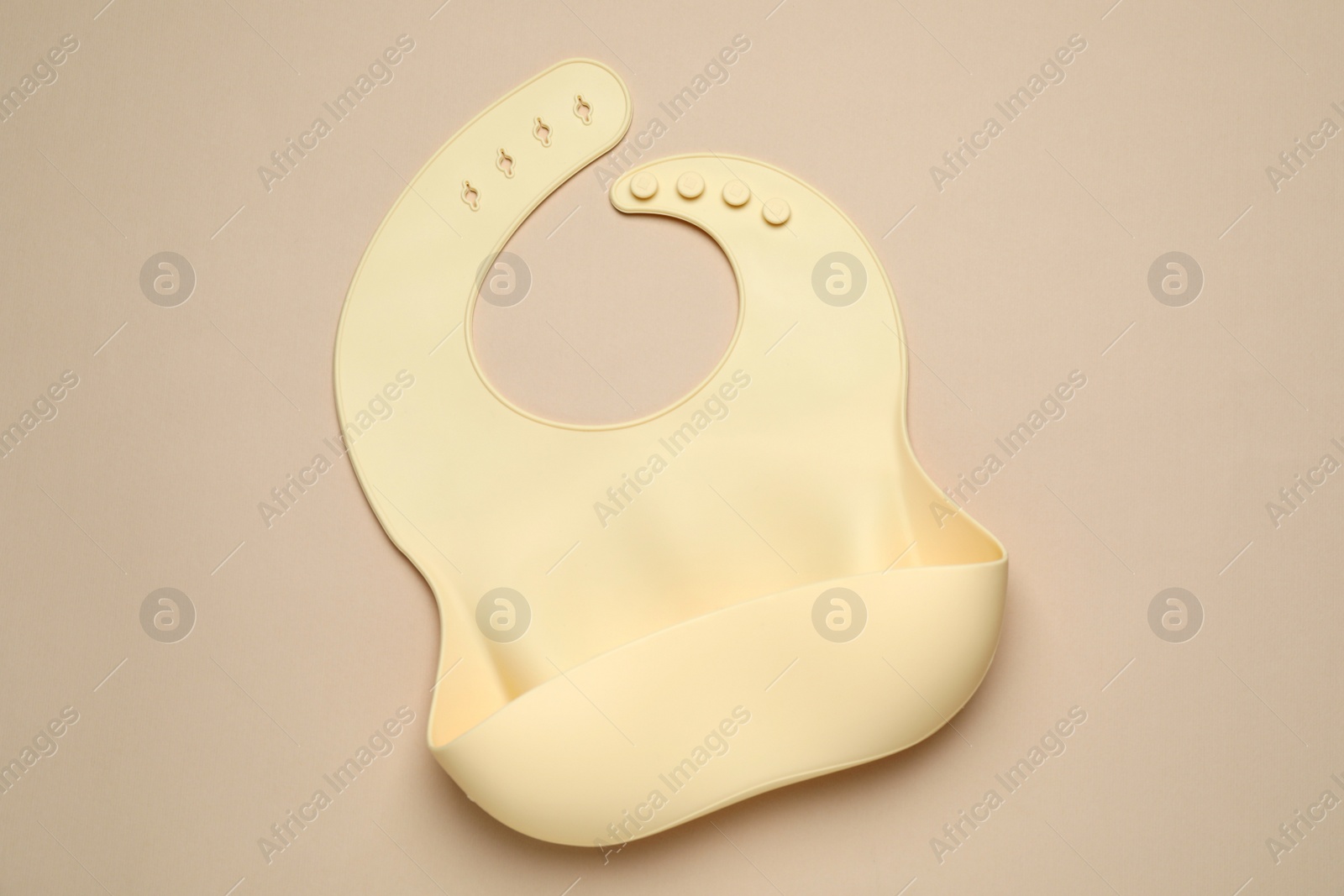 Photo of New silicone baby bib on beige background, top view. First food