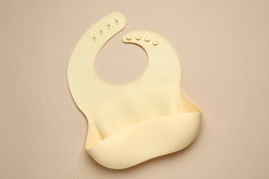 Photo of New silicone baby bib on beige background, top view. First food
