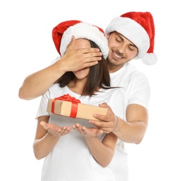 Young man giving gift box to girlfriend on white background. Happy couple celebrating Christmas