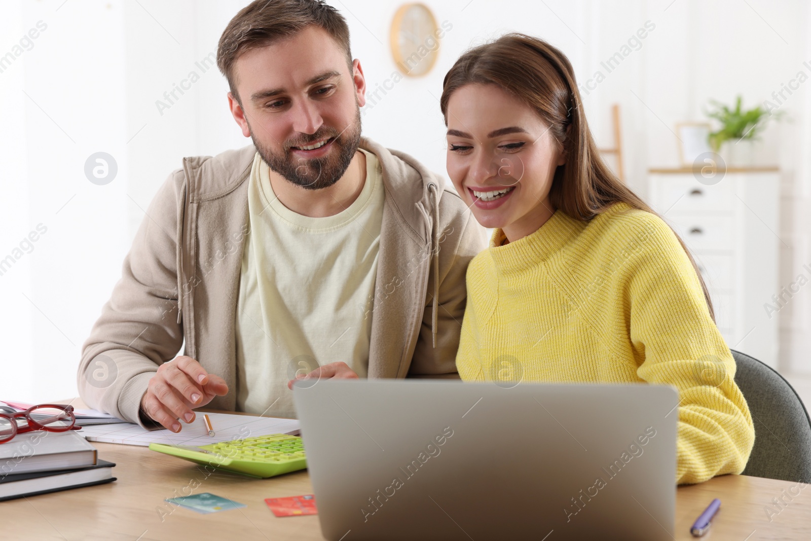 Photo of Young couple discussing family budget at table in living room