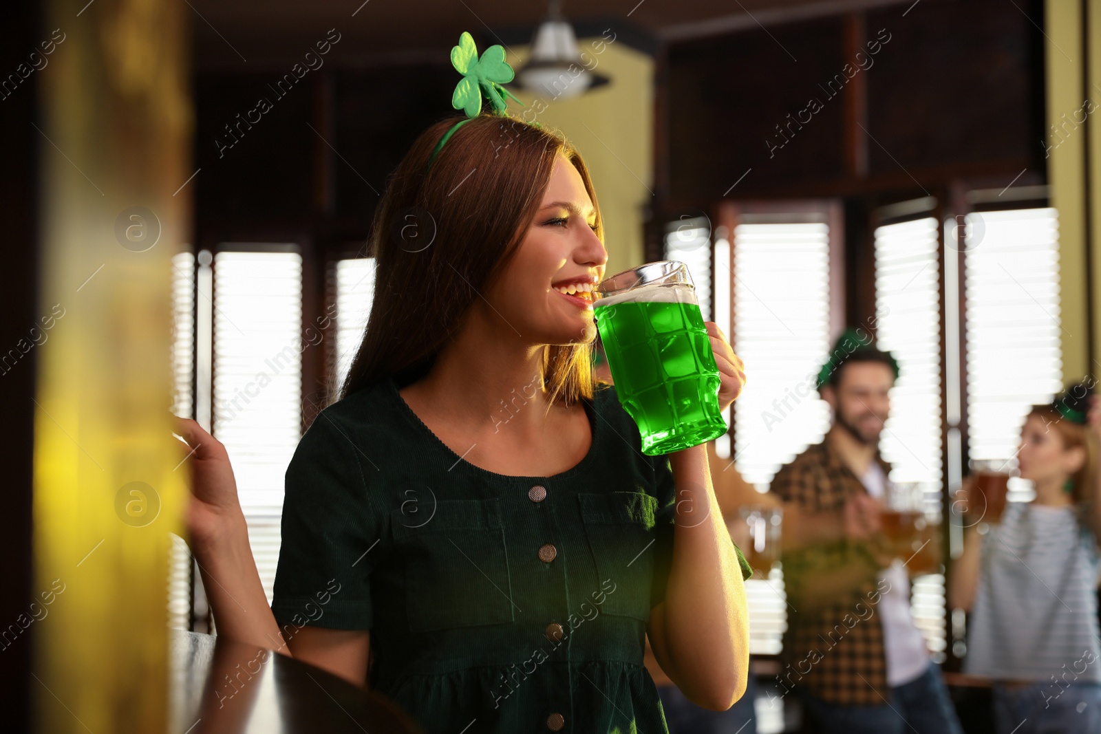 Photo of Young woman drinking green beer in pub. St. Patrick's Day celebration