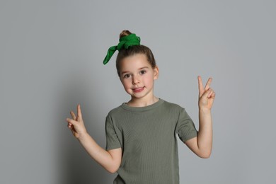 Photo of Cute little girl with stylish bandana on grey background