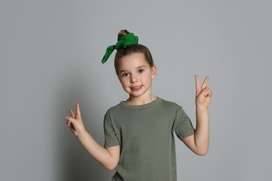 Cute little girl with stylish bandana on grey background