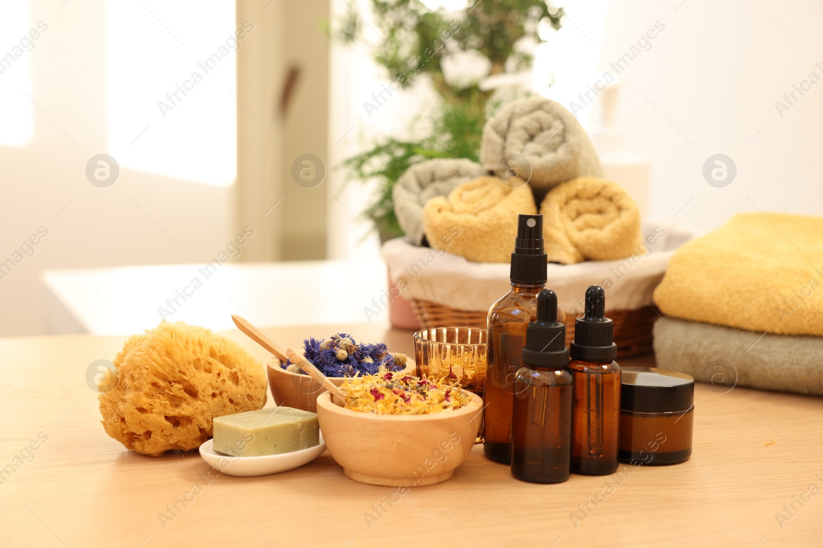 Photo of Dry flowers, loofah, soap bar, bottles of essential oils and jar with cream on wooden table indoors. Spa time