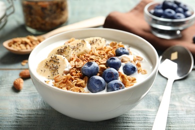 Bowl of yogurt with blueberries, banana and oatmeal on color wooden table