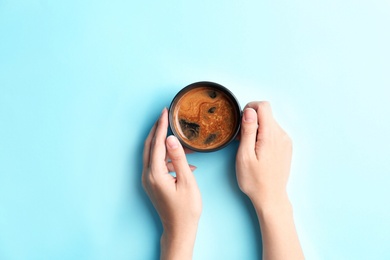 Young woman with cup of delicious hot coffee on color background, top view