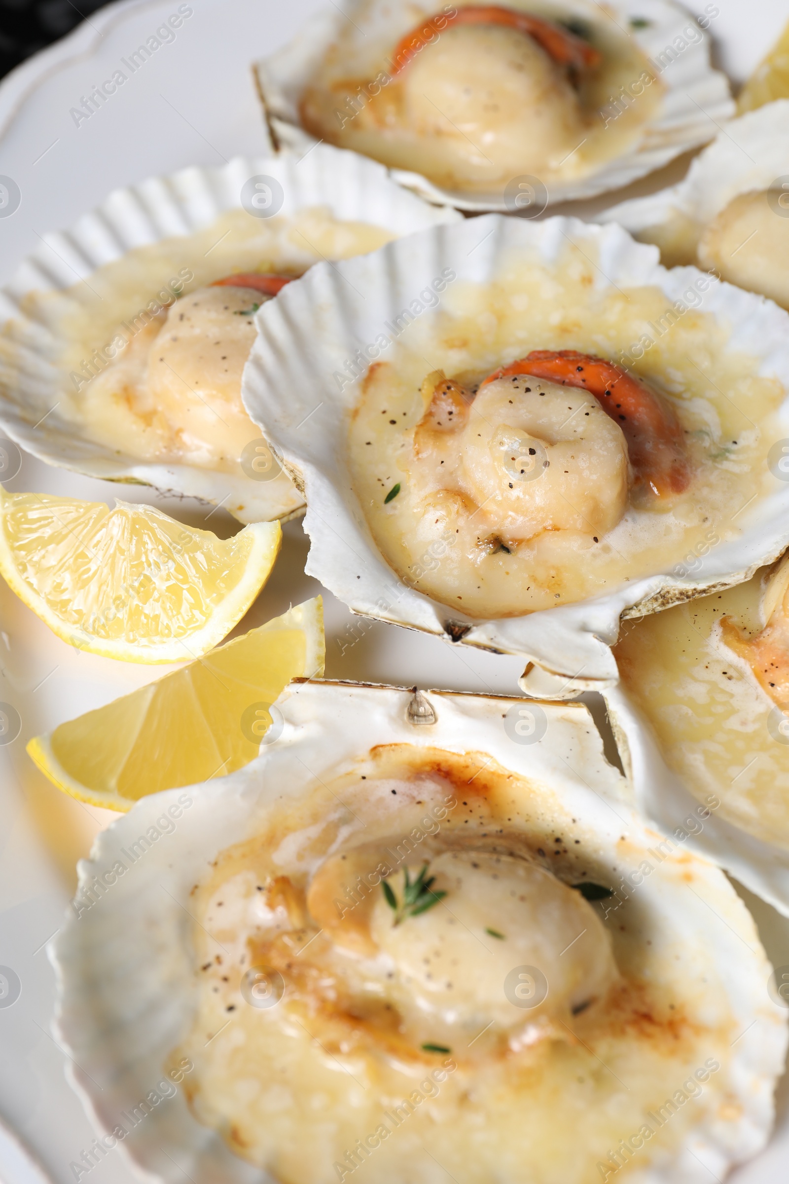 Photo of Fried scallops in shells and lemon on plate, closeup