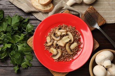 Photo of Tasty buckwheat with parsley and mushrooms on wooden table, flat lay