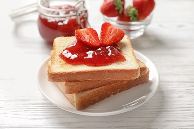 Photo of Tasty toast bread with strawberry jam and fresh berries on light background