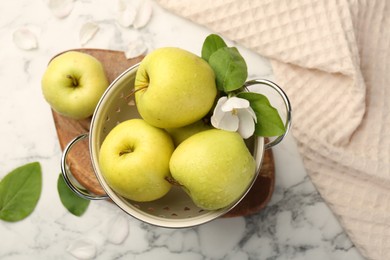 Photo of Colander with fresh apples and beautiful spring blossom on white marble table, flat lay