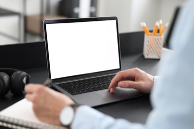 Man taking notes during webinar at table in office, closeup