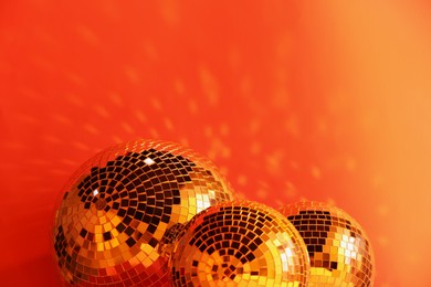 Photo of Many shiny disco balls near color wall, toned in orange. Space for text