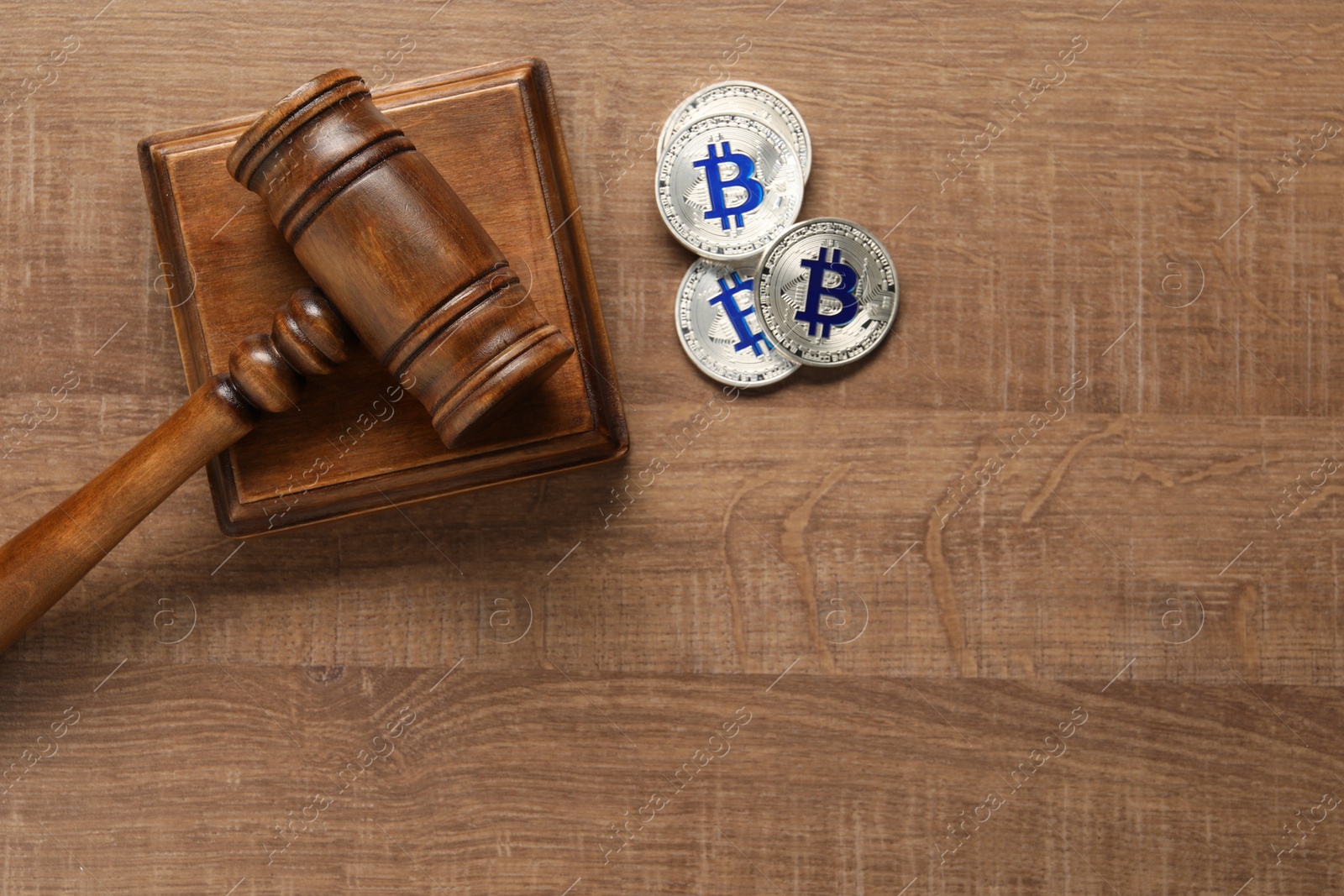 Photo of Law concept. Gavel and bitcoins on wooden table, top view. Space for text
