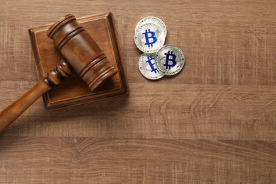 Photo of Law concept. Gavel and bitcoins on wooden table, top view. Space for text