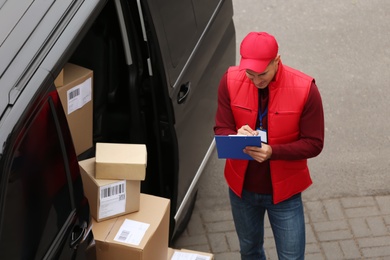 Photo of Courier checking amount of parcels in delivery van outdoors