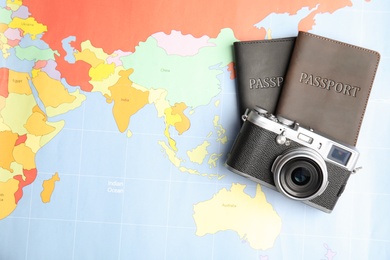Passports and camera on world map, top view. Travel agency
