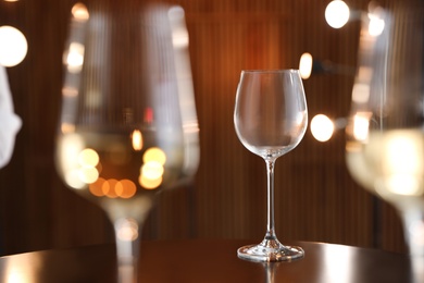 Photo of Empty wine glass on table against blurred background. Space for text