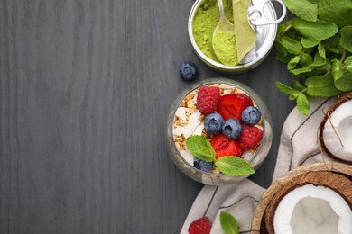 Photo of Tasty oatmeal with berries and mint on black wooden table, flat lay. Space for text. Healthy breakfast