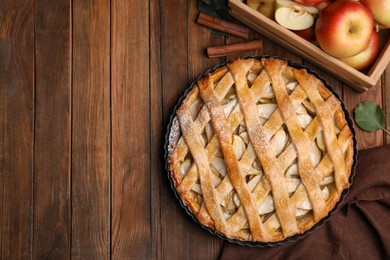 Photo of Delicious traditional apple pie on wooden table, flat lay. Space for text