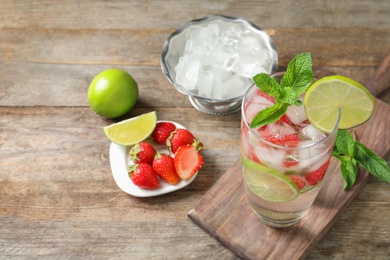 Photo of Glass of natural lemonade with lime, strawberries and mint on table