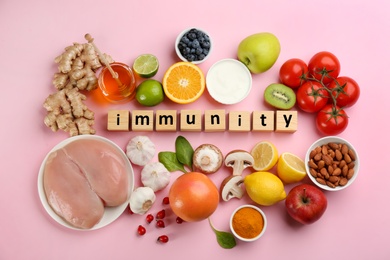 Photo of Set of natural products and cubes with word Immunity on pink background, flat lay