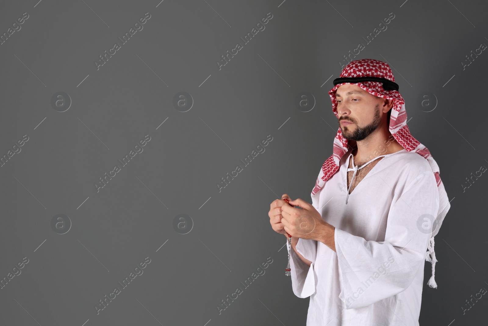 Photo of Muslim man praying on gray background. Space for text