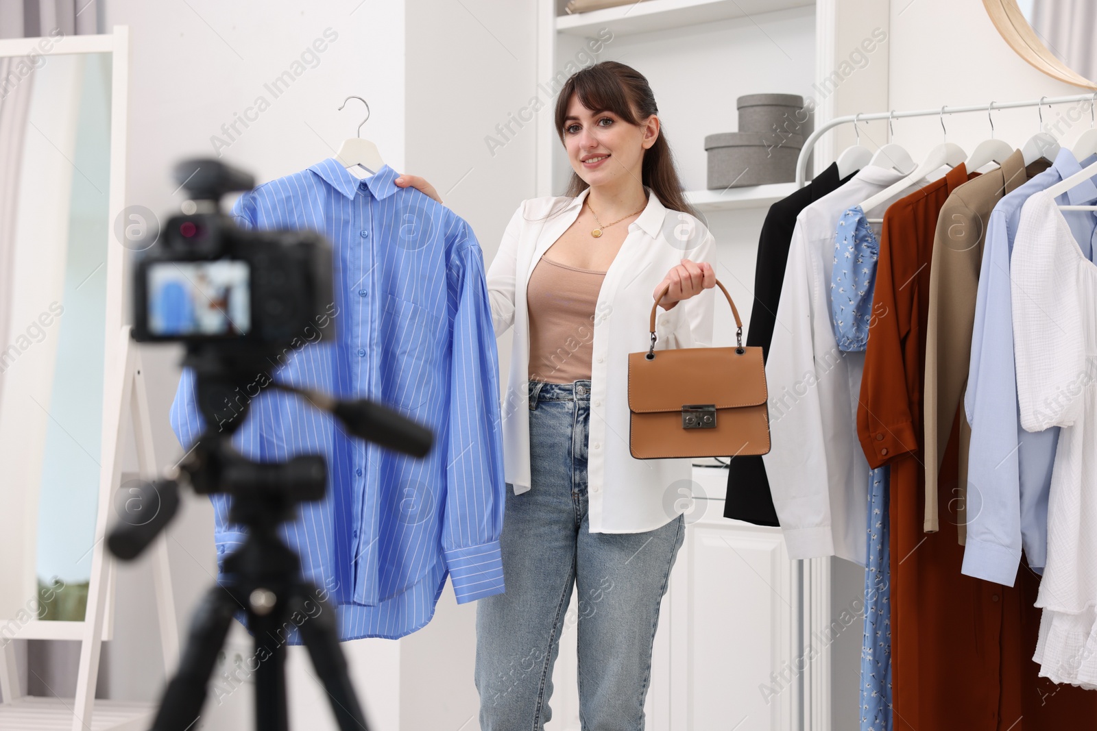 Photo of Smiling fashion blogger showing her clothes while recording video at home