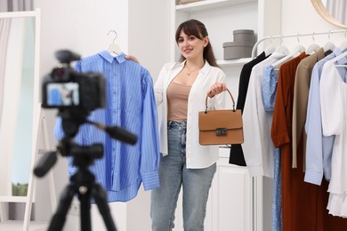Photo of Smiling fashion blogger showing her clothes while recording video at home
