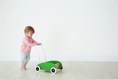 Cute baby playing with toy walker, indoors