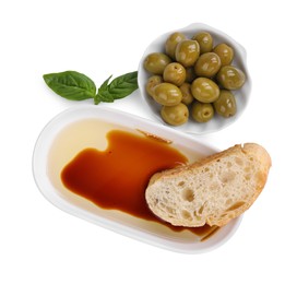 Photo of Bowl of organic balsamic vinegar with oil served with bread slice, basil and olives isolated on white, top view