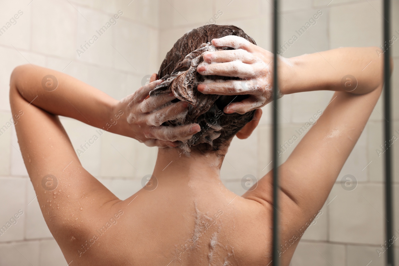 Photo of Woman washing hair while taking shower at home, back view