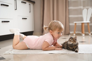 Cute little child with adorable pet on floor at home