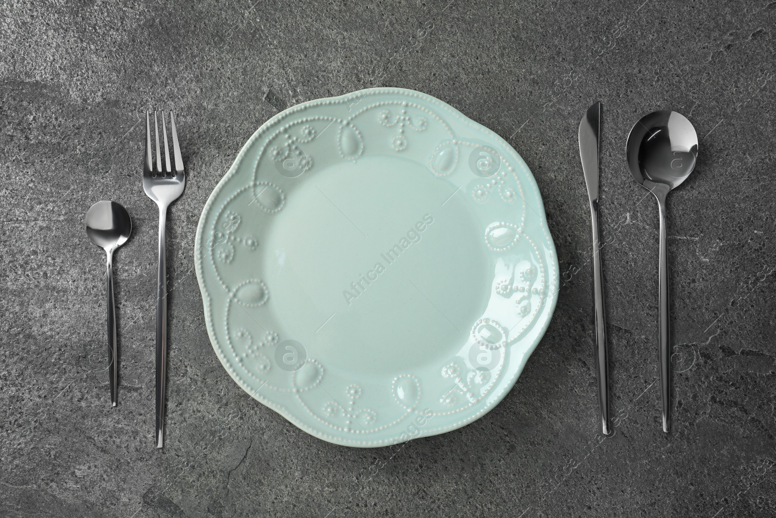 Photo of Stylish silver cutlery and plate on grey table, flat lay