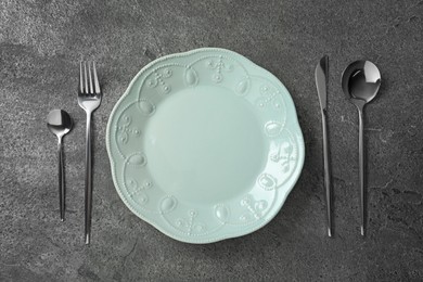 Photo of Stylish silver cutlery and plate on grey table, flat lay