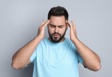 Photo of Young man suffering from headache on light grey background