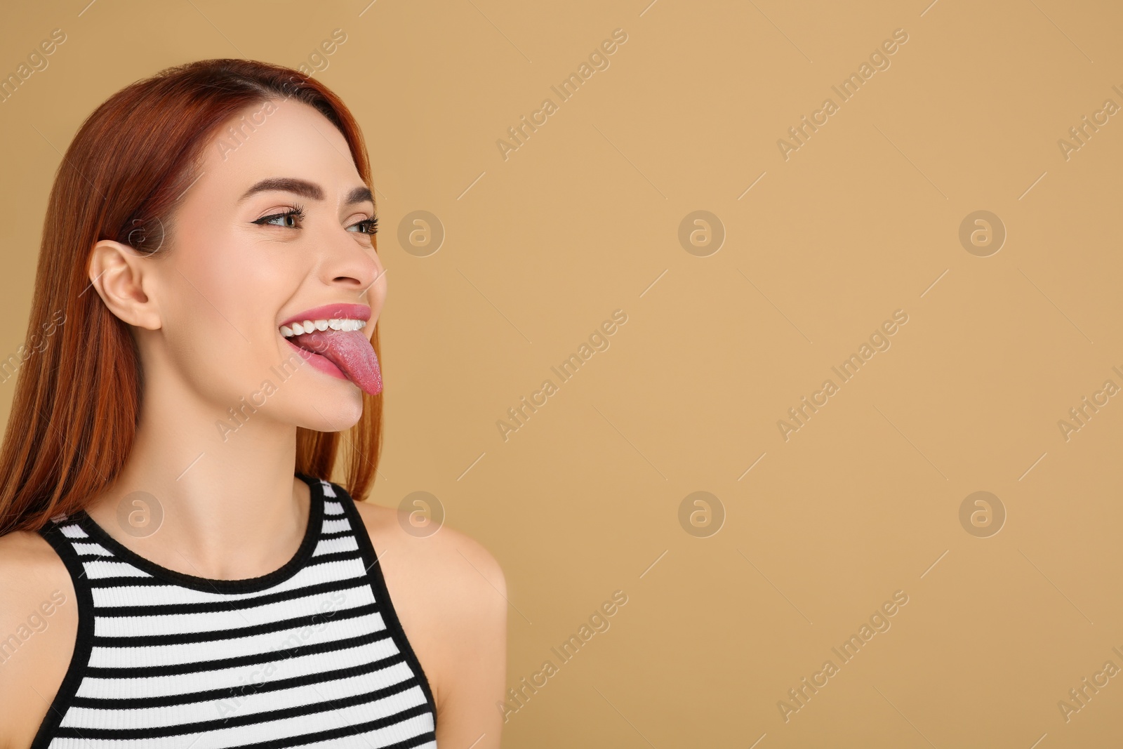 Photo of Happy woman showing her tongue on beige background. Space for text